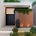 Modern outdoor entrance featuring a vertical wall clad in Serene Brown Matt Metro Tiles paired with greenery and soft lighting.