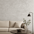 Living room interior featuring Celeste Grey Endless Marble Gloss Tiles on the wall, styled with a neutral beige sofa, black floor lamp, and round wooden coffee table with minimalist decor.