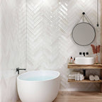 Contemporary bathroom showcasing Edgy White Glossy Metro Tiles in a herringbone pattern, paired with wood-effect walls and minimalist fixtures.