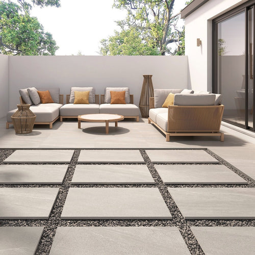 Gravel White Outdoor Tile used on a spacious patio with modern garden furniture and raised seating area.