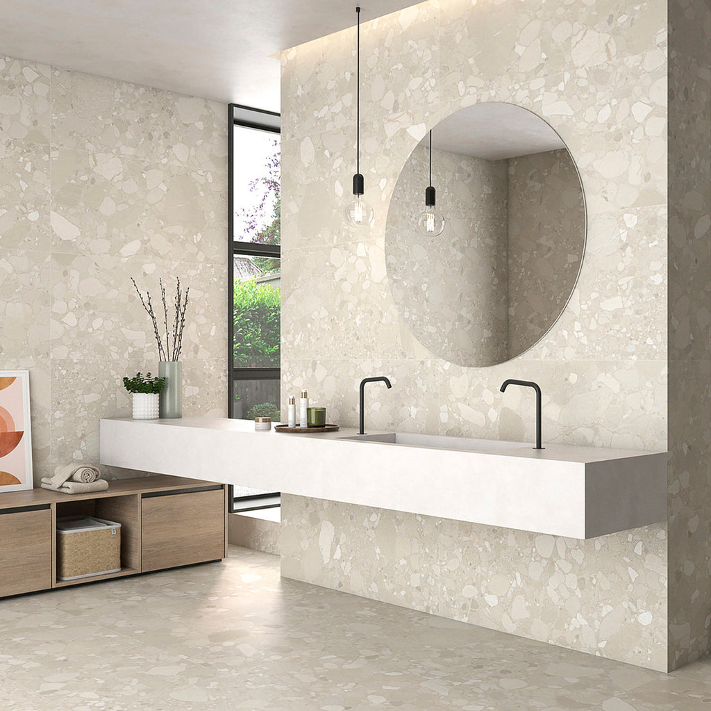Modern bathroom featuring Roca Beige Terrazzo Matt tiles on walls and floors with a floating sink and round mirror.