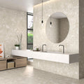 Modern bathroom featuring Roca Beige Terrazzo Matt tiles on walls and floors with a floating sink and round mirror.