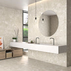 Modern bathroom featuring Roca Beige Terrazzo Matt tiles on walls and floors with a floating sink and round mirror.