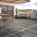 Outdoor patio setting featuring Slater Dark Grey 60x90cm tiles with a modern garden lounge and timber dining furniture.