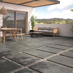 Outdoor patio setting featuring Slater Dark Grey 60x90cm tiles with a modern garden lounge and timber dining furniture.